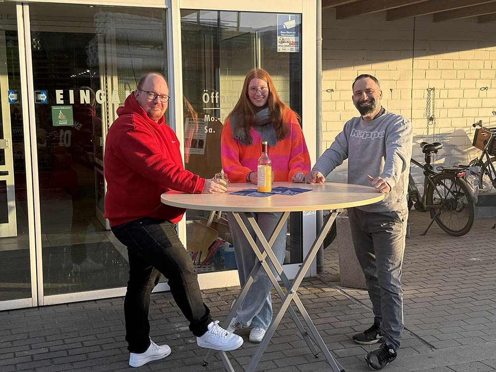 drei menschen an einem stehtisch